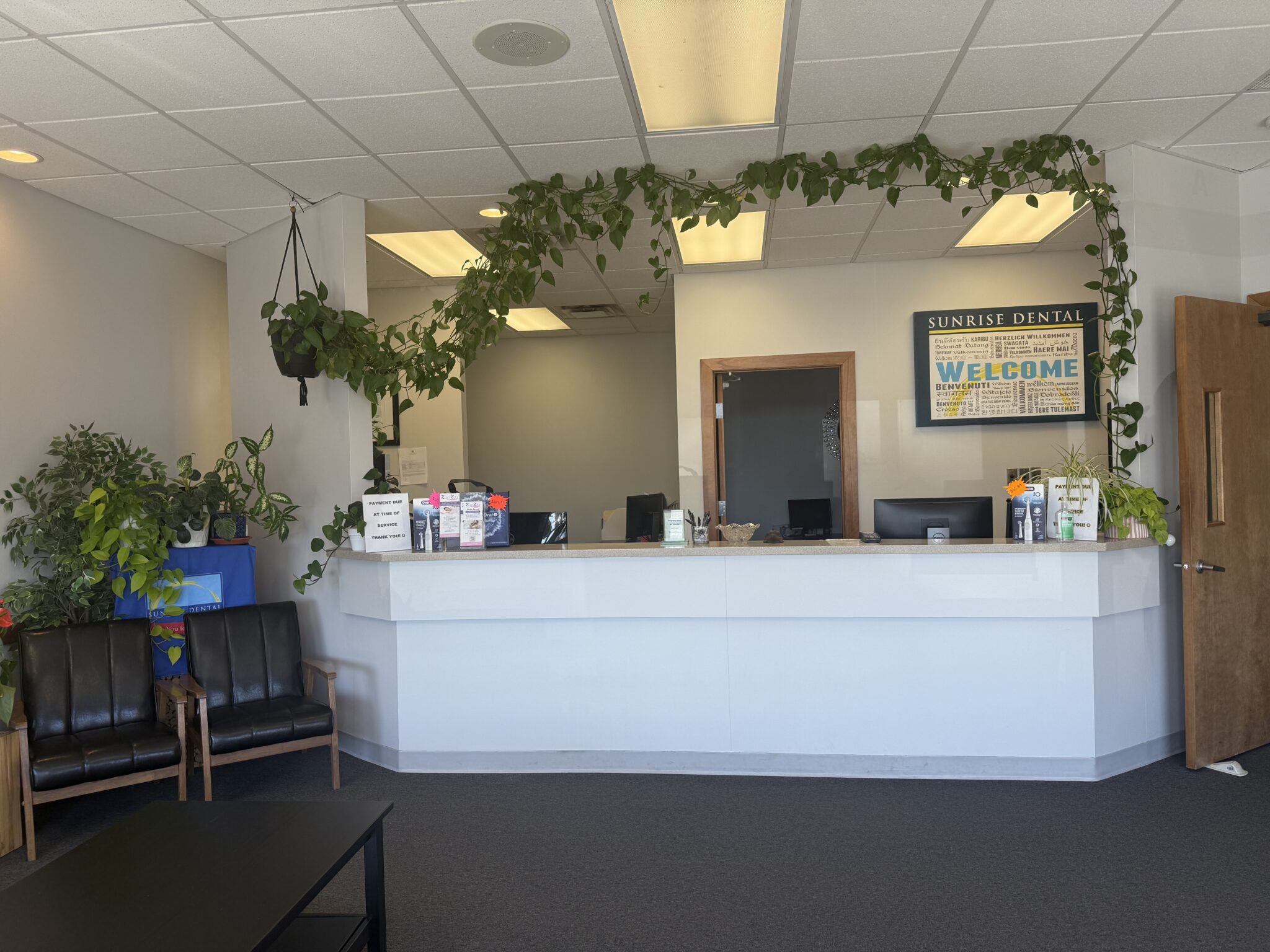 Front desk and reception area of Sunrise Dental office with indoor plants, welcome sign, and seating for patients — modern dental clinic interior in Yakima, Washington